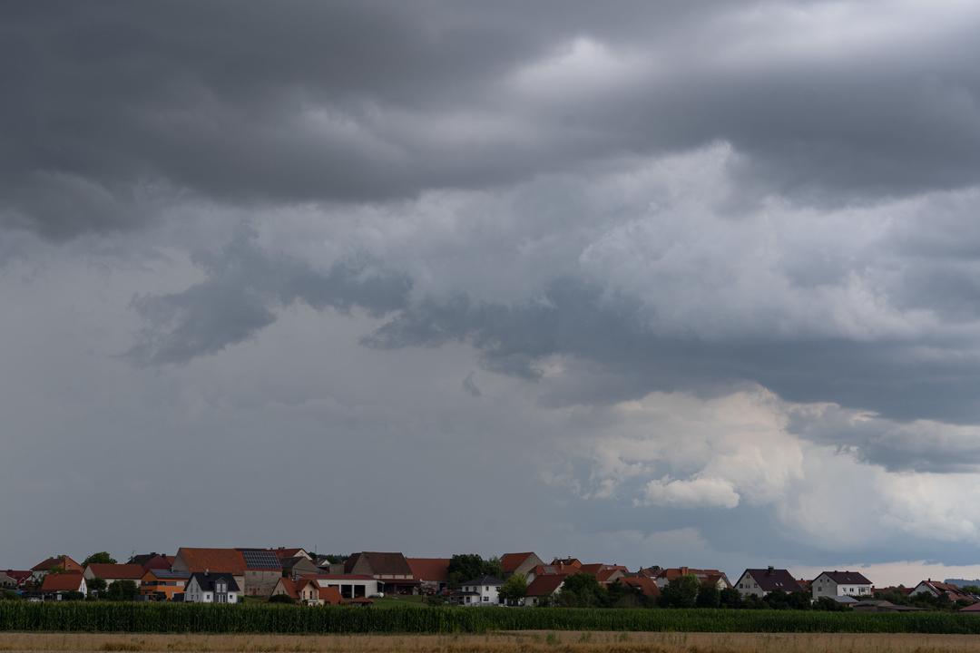 Dunkle Gewitterwolken und Regenschauer ziehen über die Ortschaft in Oberfranken hinweg (Archivbild). | Bild:dpa-Bildfunk/Nicolas Armer