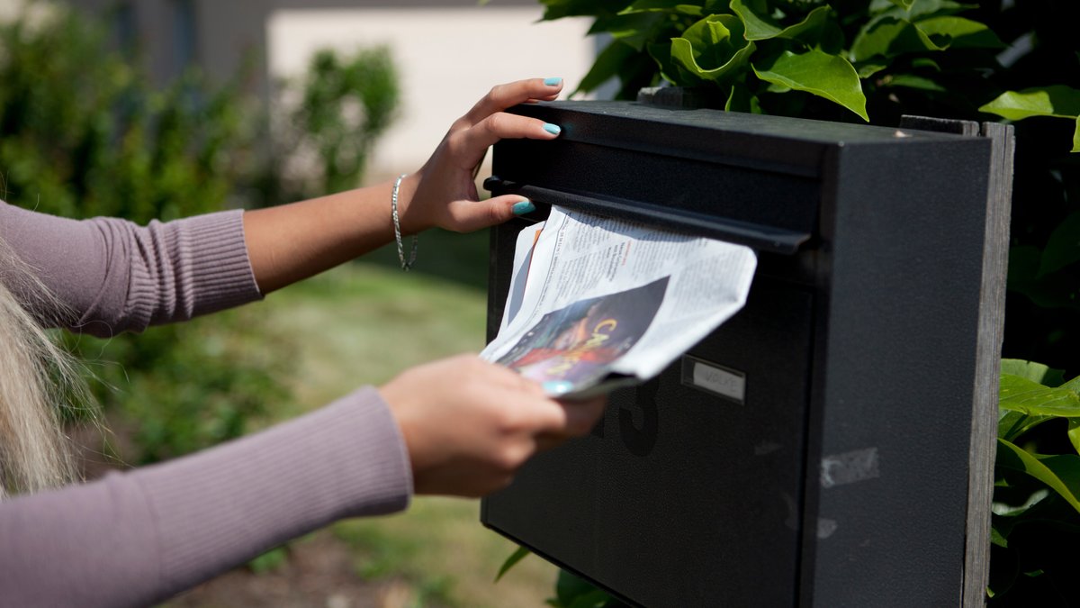Symbolbild: Eine Schülerin wirft Werbeprospekte in einem Briefkasten