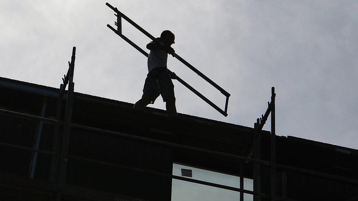 Ein Arbeiter trägt auf einer Baustelle ein Teil eines Baugerüsts (Symbolbild). 