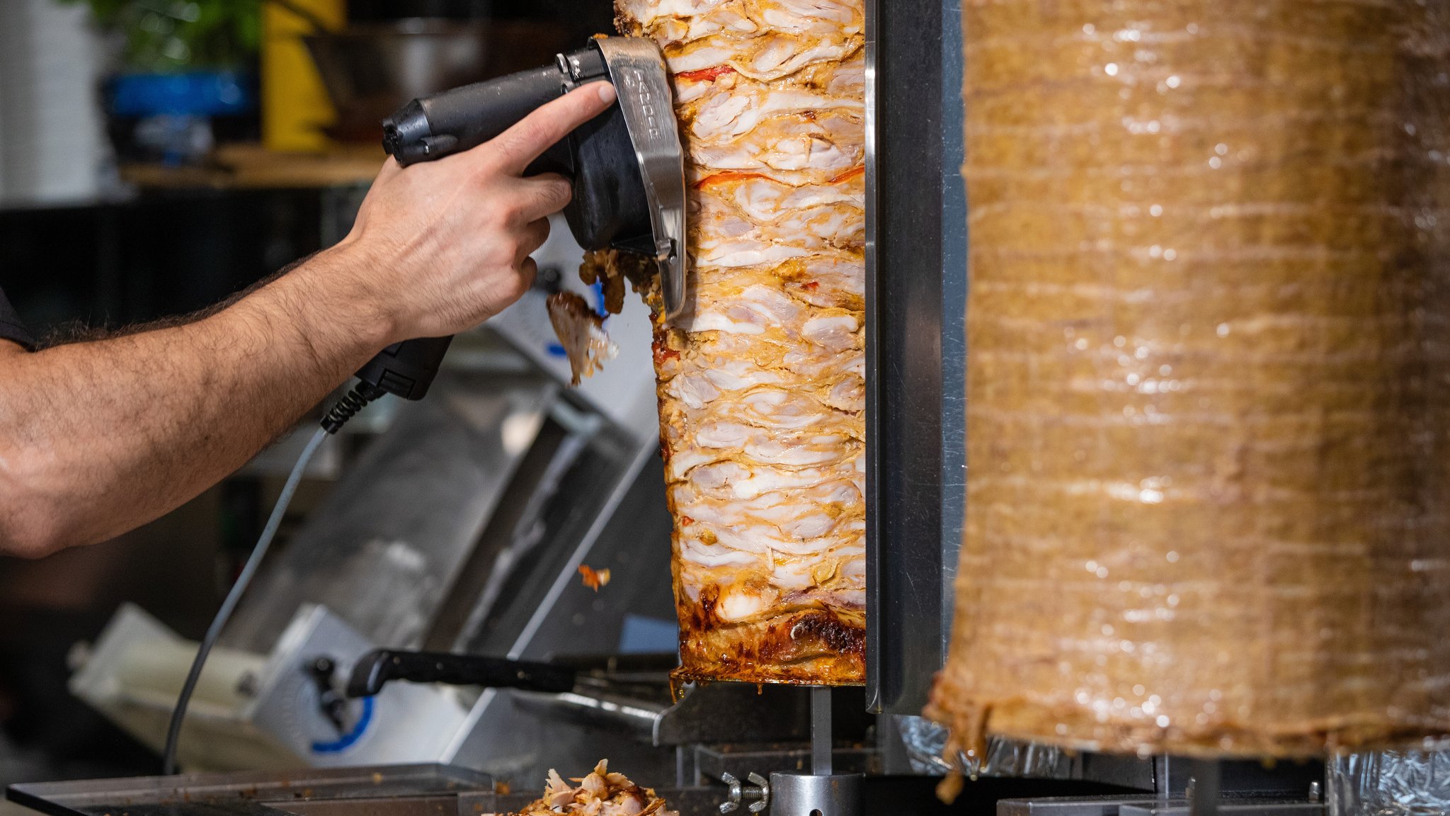 (Symbolbild) Ein Mitarbeiter einer Dönerbude schneidet Fleisch von einem Dönerspieß.