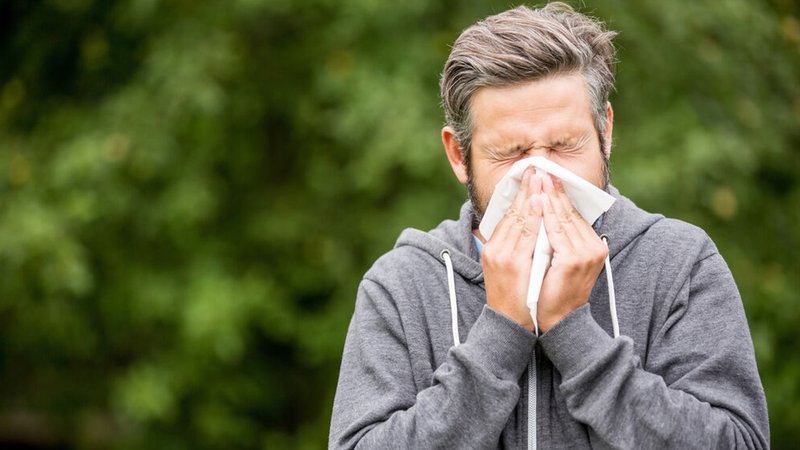 Ein erkälteter Mann, schnäutzt in ein Taschentunch. | Bild: stock.adobe.com/Robert Kneschke Ein erkälteter Mann, schnäutzt in ein Taschentunch.