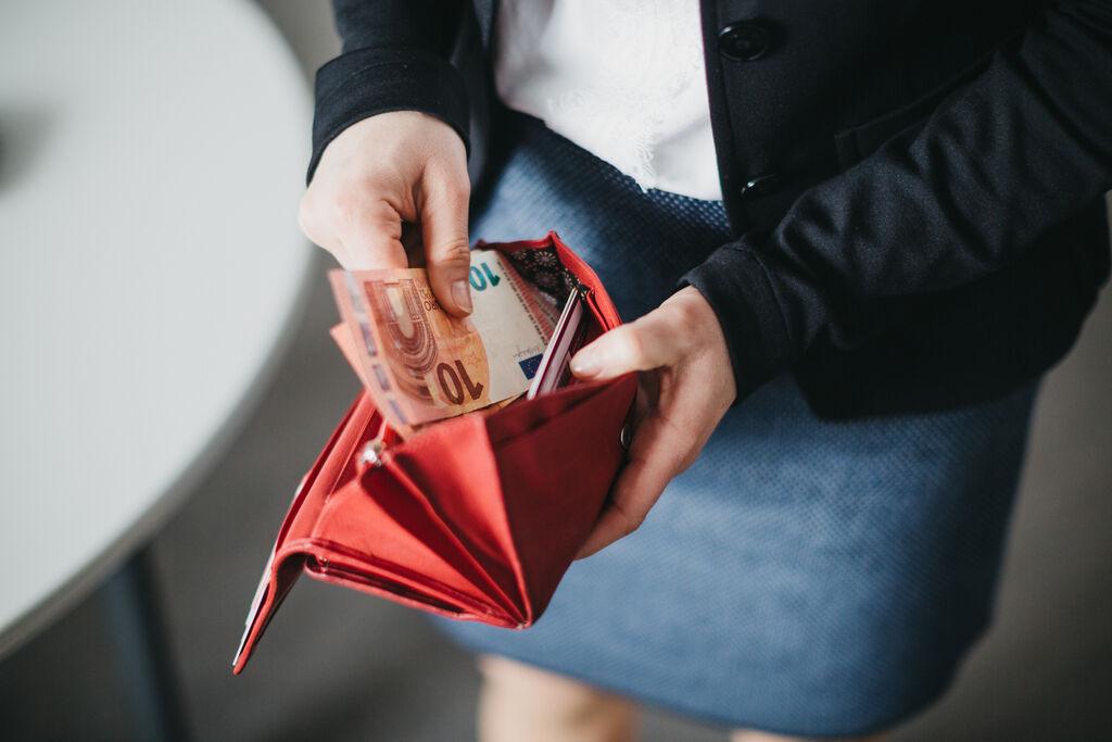 Eine Frau die Geld in ihren Geldbeutel steckt.