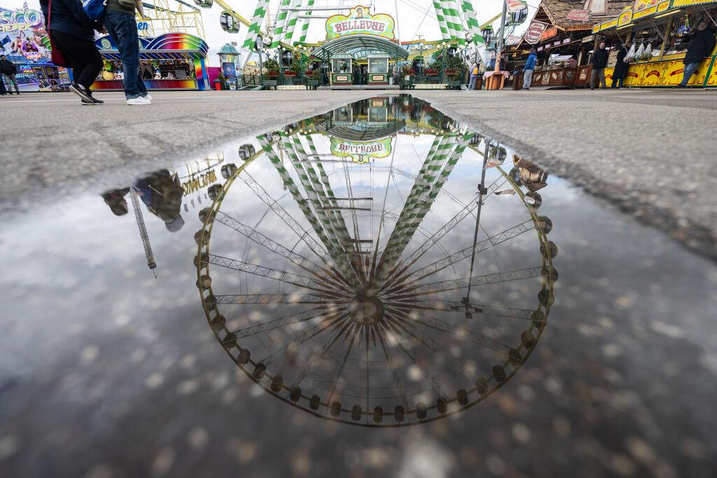 Ein Riesenrad spiegelt sich in einer Pfütze auf dem Festgelände des Stuttgarter Frühlingsfestes. 