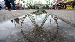 Ein Riesenrad spiegelt sich in einer Pfütze auf dem Festgelände des Stuttgarter Frühlingsfestes.  | Bild:dpa-Bildfunk/Marijan Murat