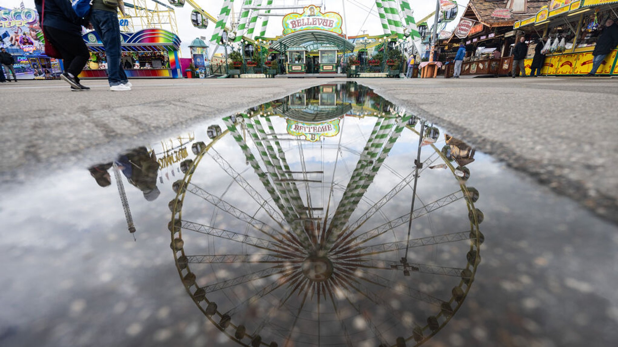 Ein Riesenrad spiegelt sich in einer Pfütze auf dem Festgelände des Stuttgarter Frühlingsfestes. 