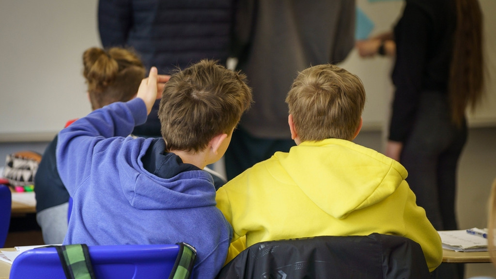 Zwei aus der Ukraine geflüchtete Schüler sitzen beim Deutschunterricht im Gymnasium bei einer Übung an ihren Tischen.