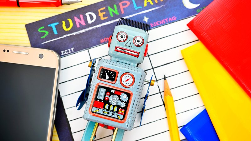 Symbolbild: Roboter umgeben von Schulutensilien. | Bild: picture alliance / CHROMORANGE | Christian Ohde Symbolbild: Roboter umgeben von Schulutensilien.