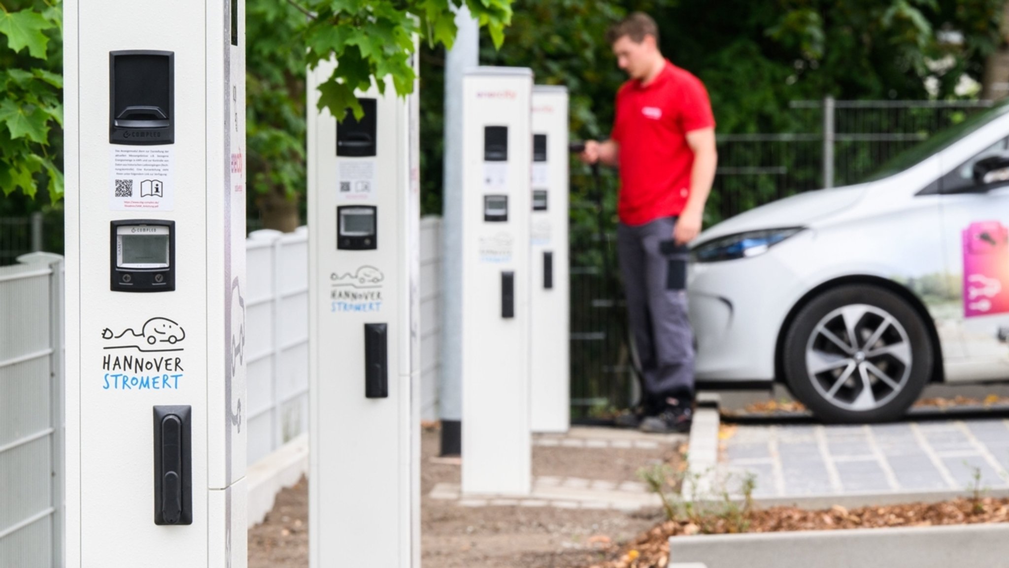 Ein Enercity-Mitarbeiter steht im Juli 2022 mit einem Elektroauto neben Ladesäulen in einem neuen Ladepark (gestellte Szene bei Fototermin). Der Regionalversorger Enercity eröffnet in Hannover im Stadtteil List einen Ladepark für Elektroautos. Anwohnern stehen 84 Ladepunkte mit 22 kW Leistung und sechs Schnellladepunkte mit je max. 150 kW Leistung zur Verfügung. 60 Ladesäule sind bereits für 30 Jahre vermietet.