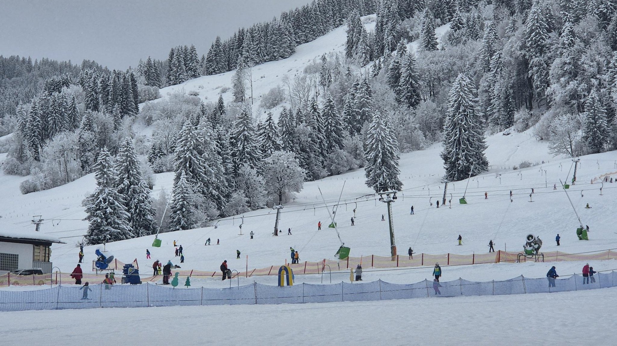 Schneebedeckte Hänge und voll besetzte Skilifte in Bolsterlang