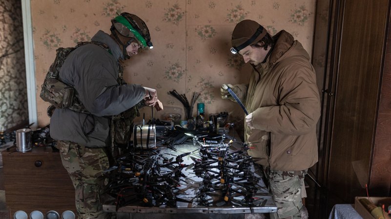 Zwei Männer stehen vor einem Tisch, auf dem Drohnen-Komponenten liegen | Bild: Diego Herrera Carcedo/Picture Alliance Zwei Männer stehen vor einem Tisch, auf dem Drohnen-Komponenten liegen