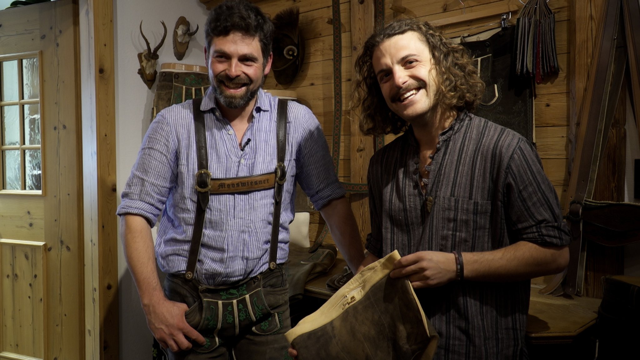 Die beiden Lederhosenmacher Engelbert und Michael Aigner lächeln in die Kamera und zeigen Boxershorts aus Leder.