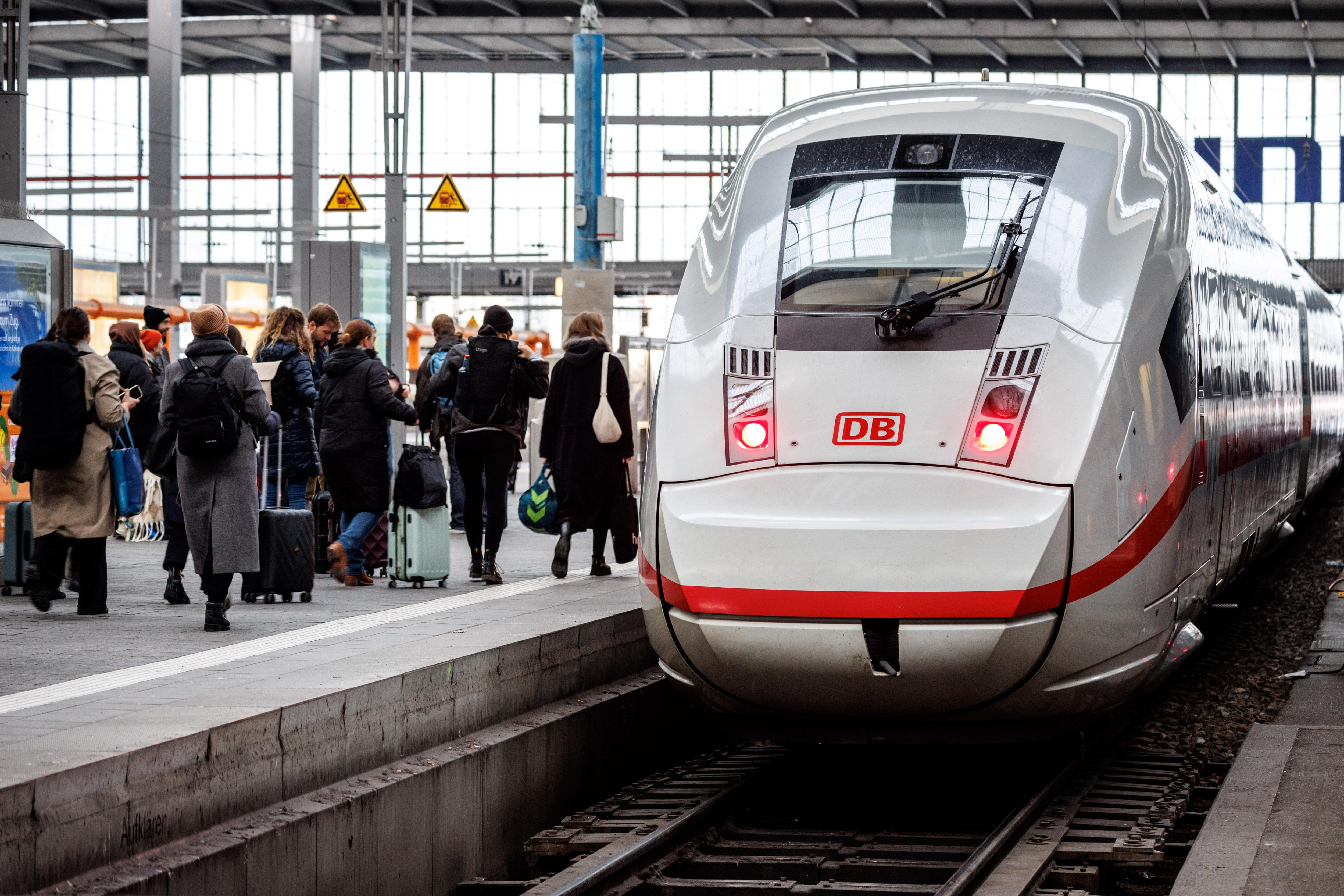 Reisende gehen zu einem ICE, der an einem Gleis am Hauptbahnhof wartet.
