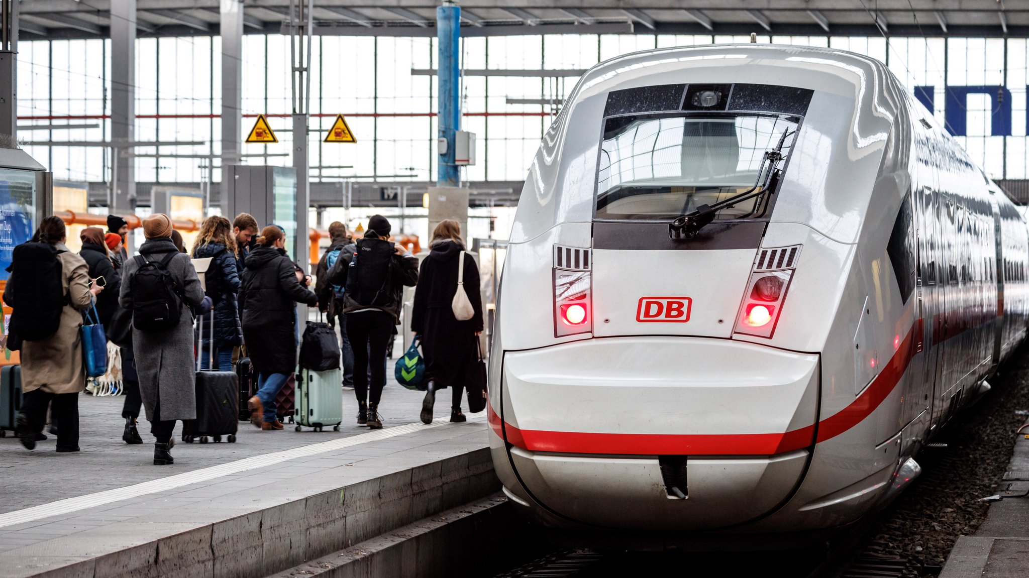 Reisende gehen zu einem ICE, der an einem Gleis am Hauptbahnhof wartet.