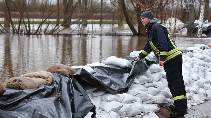 Ein Feuerwehrmann kontrolliert in Oberröblingen einen Deich aus Sandsäcken. | Bild: picture alliance/dpa | Jan Woitas Ein Feuerwehrmann kontrolliert in Oberröblingen einen Deich aus Sandsäcken.