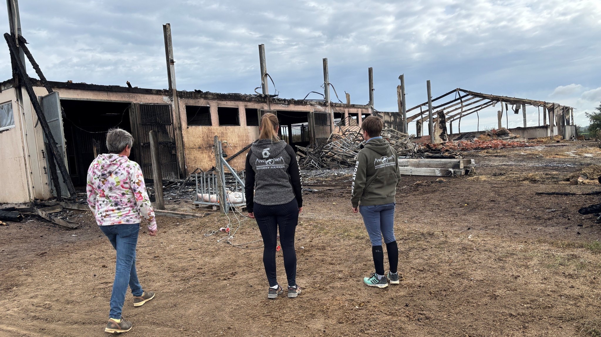 Nach dem Großbrand auf ihrem Reiterhof steht Familie Zoller vor den abgebrannten Ställen und Hallen. | Bild: BR/Judith Zacher Nach dem Großbrand auf ihrem Reiterhof steht Familie Zoller vor den abgebrannten Ställen und Hallen.