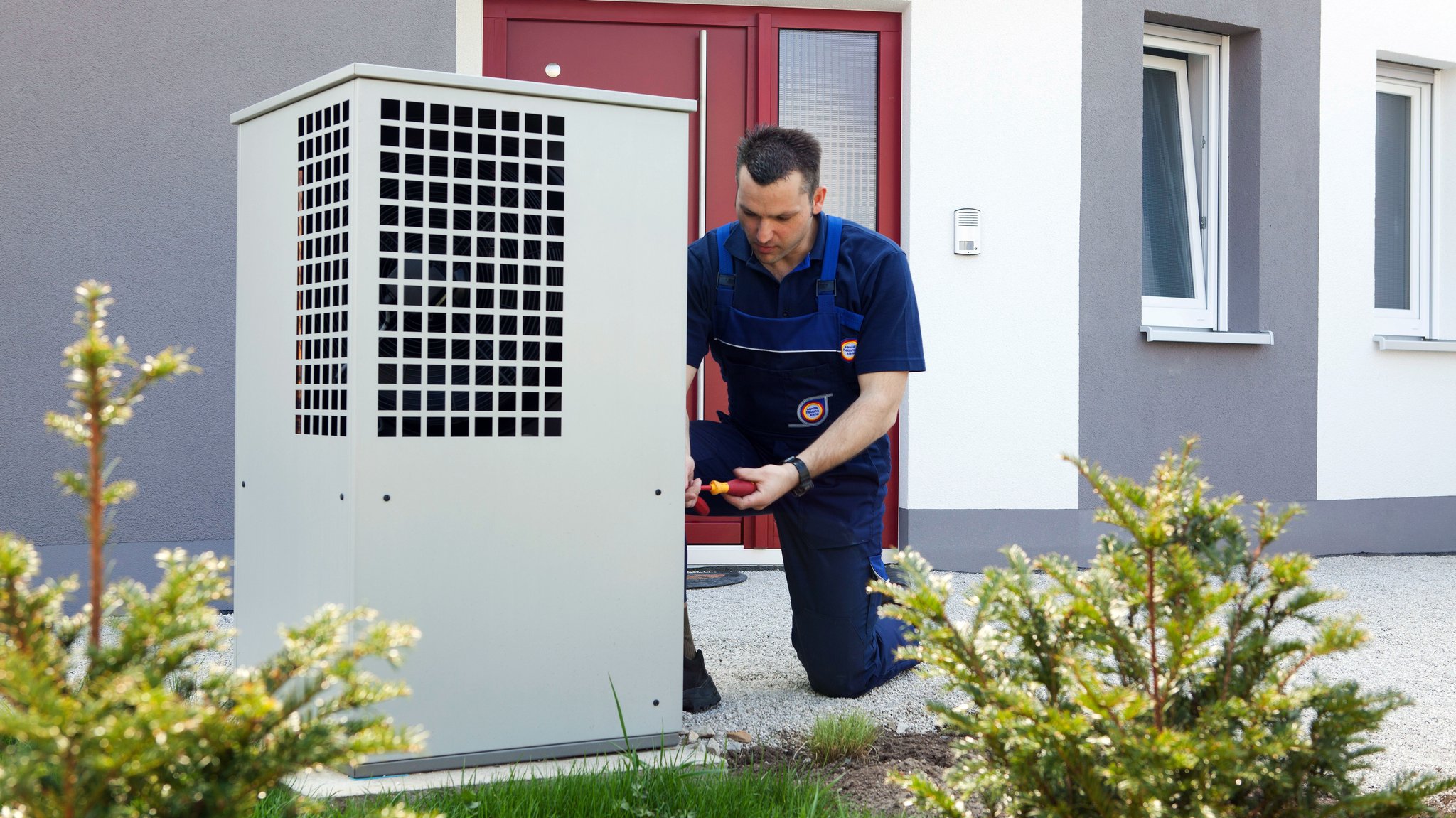 Ein Heizungsmonteur montiert das Gehäuse für eine Wärmepumpe im Rahmen einer Heizungsmodernisierung. 