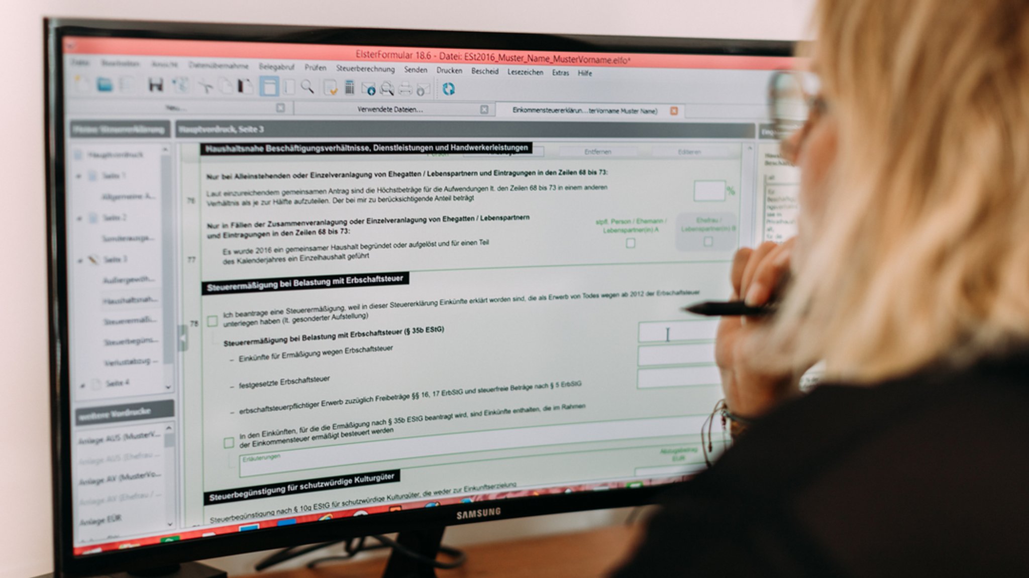 Eine Frau sitzt am Schreibtisch vor einem Bildschirm und macht ihre elektronische Steuererklärung.