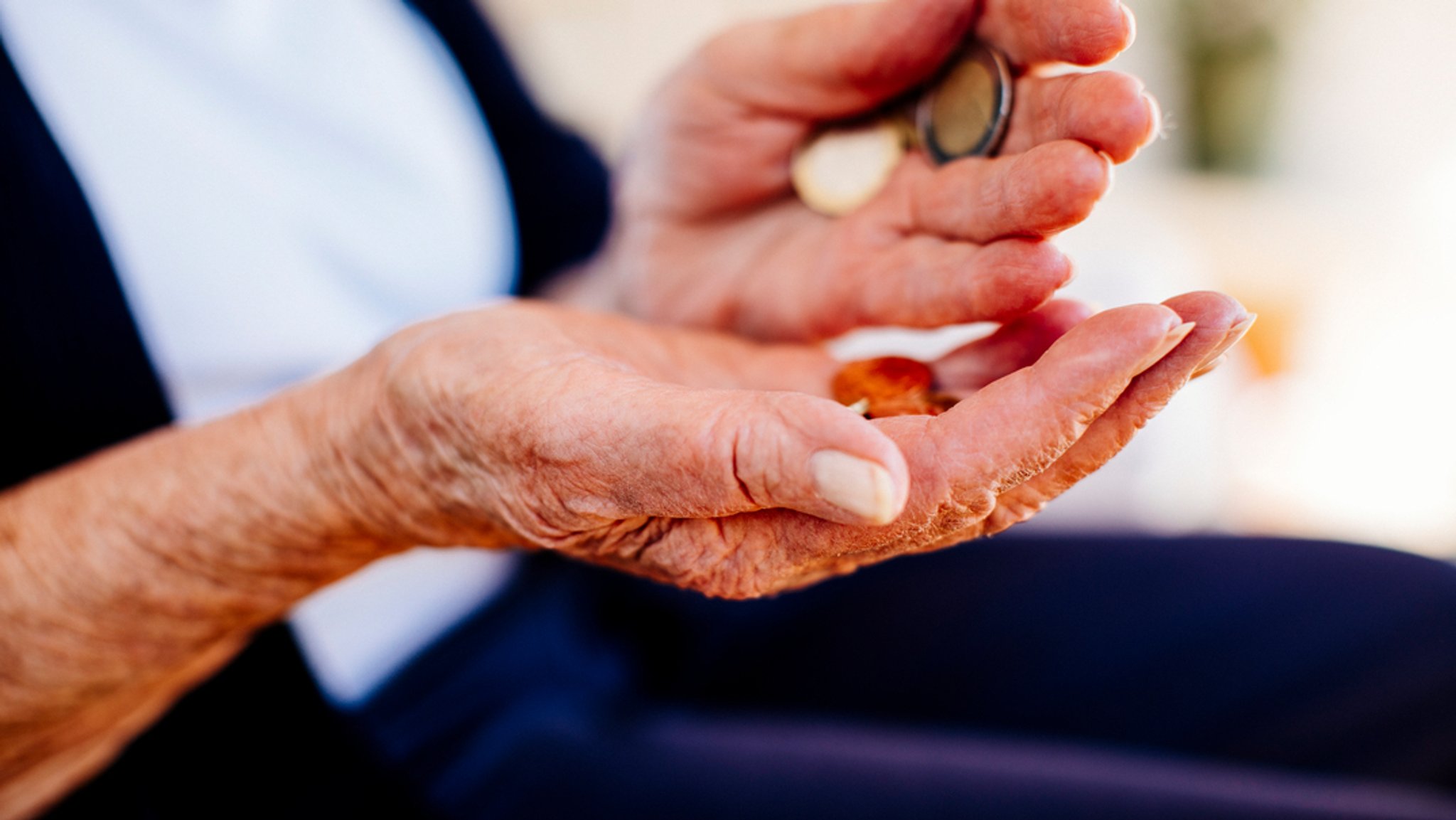 Eine alte Frau mit Geldmünzen in der Hand