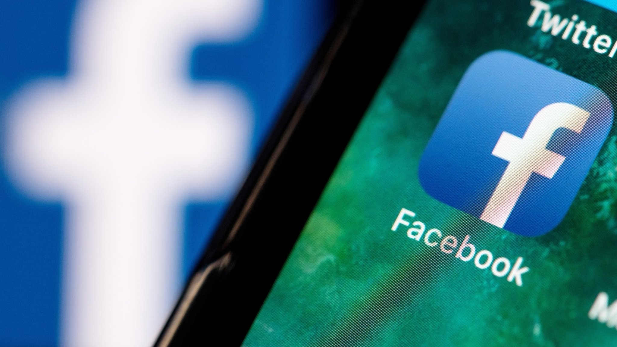 Illustration: Auf dem Bildschirm eines Smartphones steht das Logo der Facebook-App.