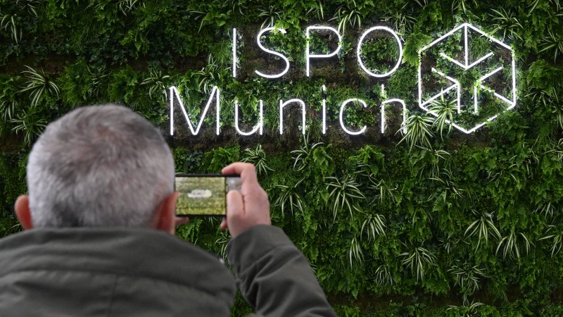 Ein Besucher fotografiert das Logo der Sportartikelmesse Ispo in der Eingangshalle der Messe München. | Bild: picture alliance/dpa | Felix Hörhager Ein Besucher fotografiert das Logo der Sportartikelmesse Ispo in der Eingangshalle der Messe München.
