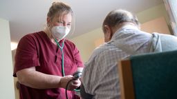 Mitarbeiterin eines Seniorenhaus in Baden-Württemberg betreut einen Bewohner | Bild:dpa-Bildfunk/Marijan Murat