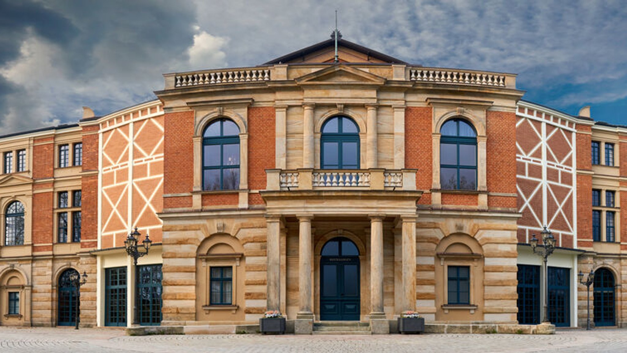 Ein Panoramabild vom Festspielhaus in Bayreuth bei bewölktem Himmel.