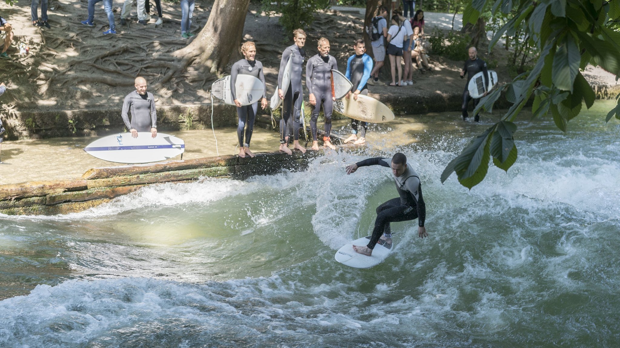 Surfer auf der stehenden Eisbachwelle in München. 