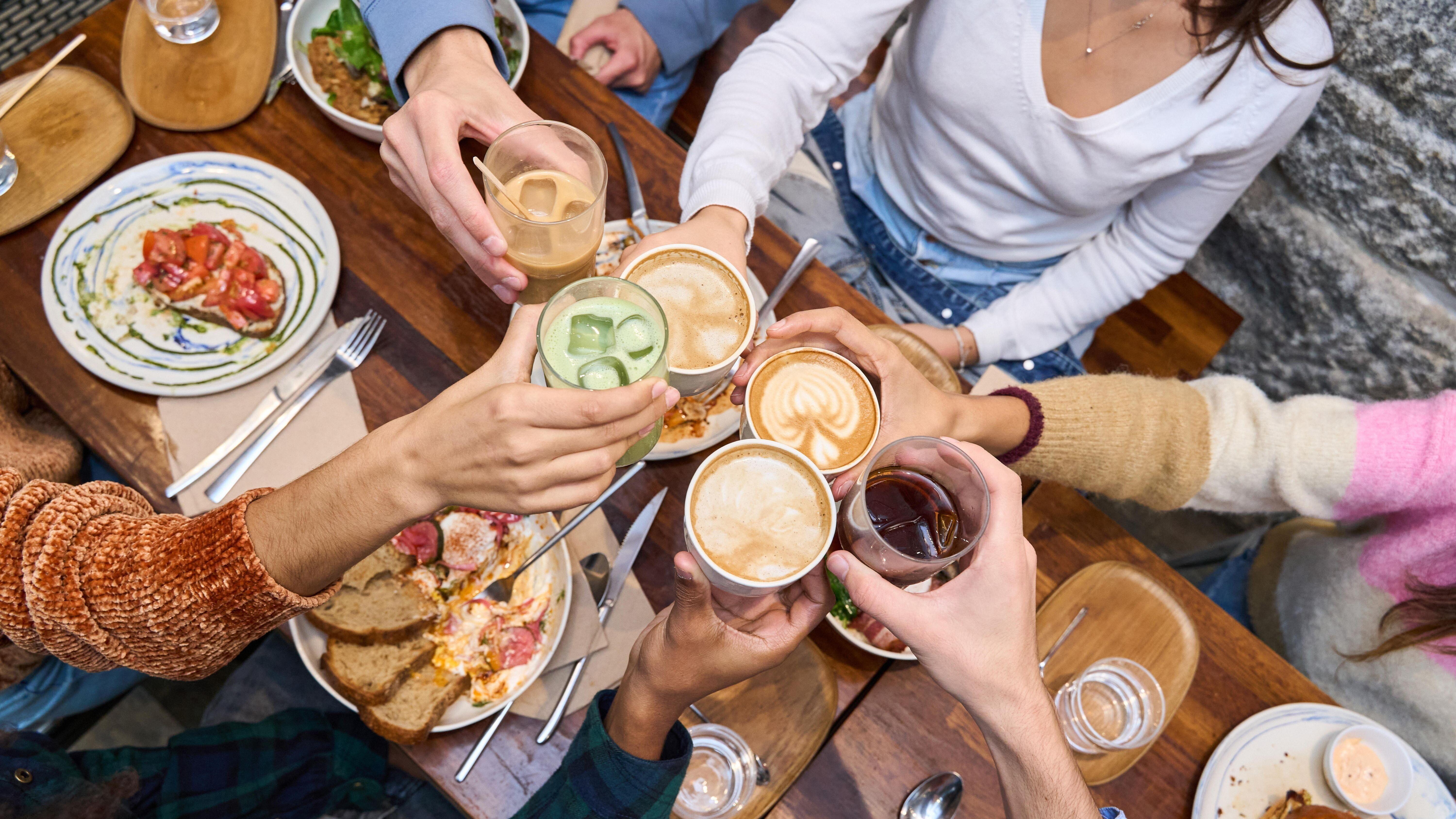 Junge Menschen prosten sich in einem Restaurant zu.
