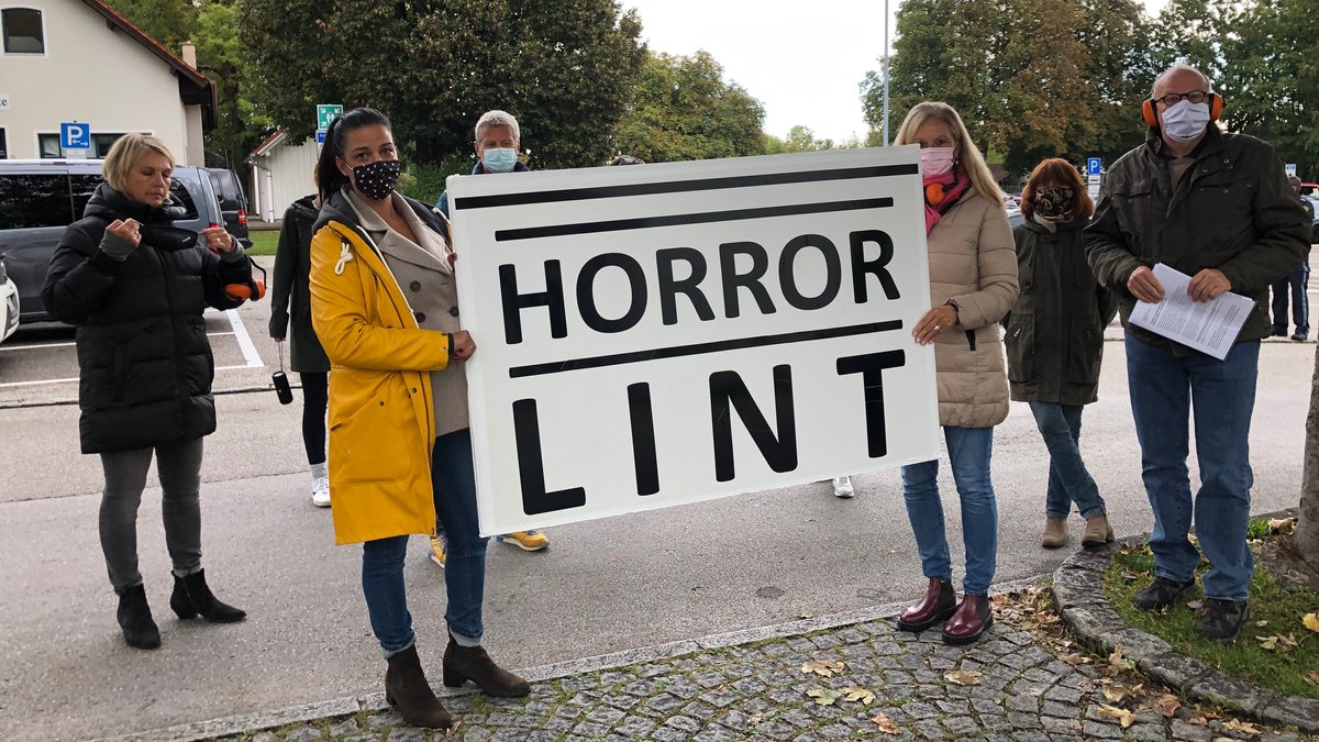 Anwohner halten ein Plakat mit der Aufschrift "Horror Lint" hoch. 