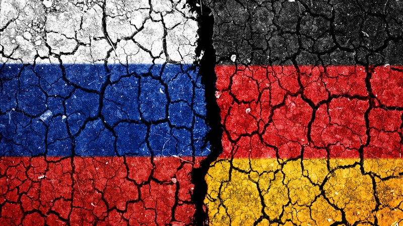 Länderflaggen von Deutschland und Russland auf einer gebrochenen Wand. 