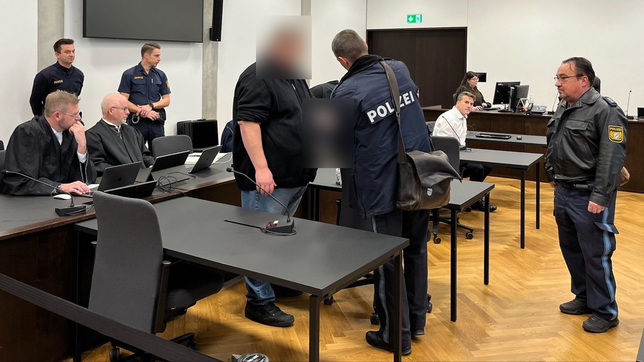 Der Bürgermeister der Gemeinde Seeg im Ostallgäu und der frühere Leiter des örtlichen Seniorenheims zwischen Polizisten und Anwälten im Gerichtssaal.