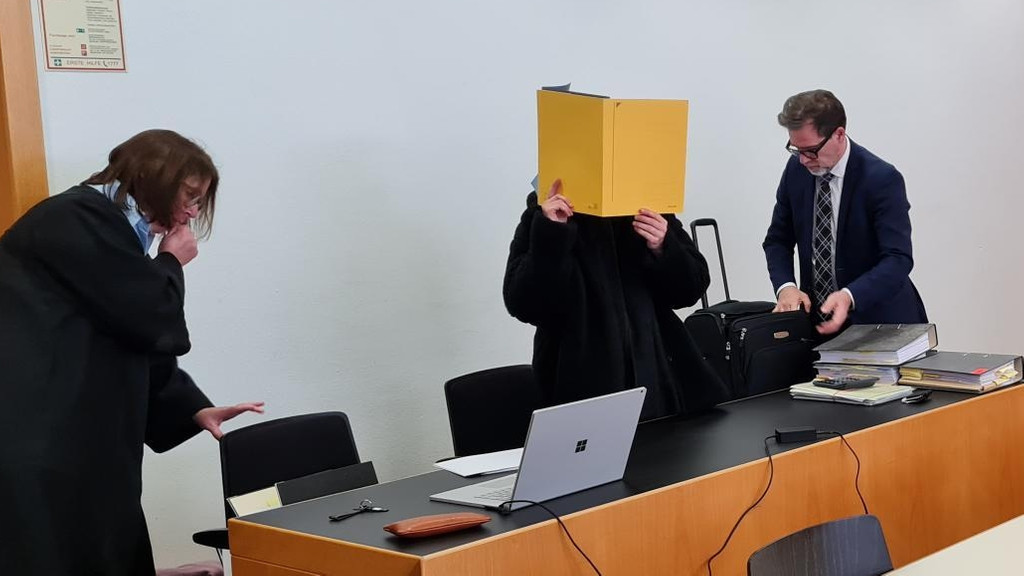 Die angeklagte Apothekerin verdeckt im Gerichtssaal ihr Gesicht