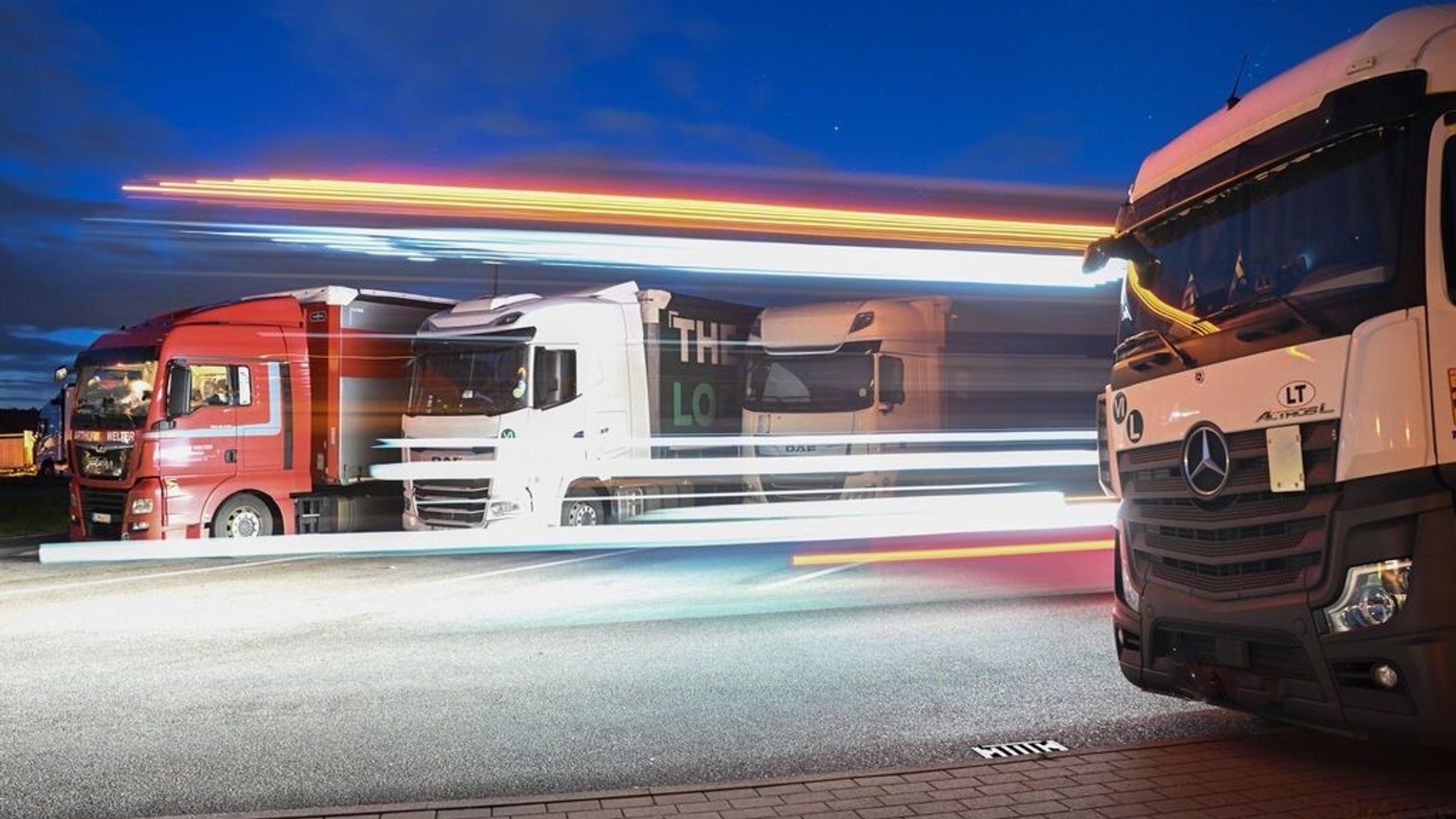 Lastwagen stehen in der Nacht auf einer Raststätte auf der Autobahn 8 bei Denkendorf während ein Lastwagen startet.