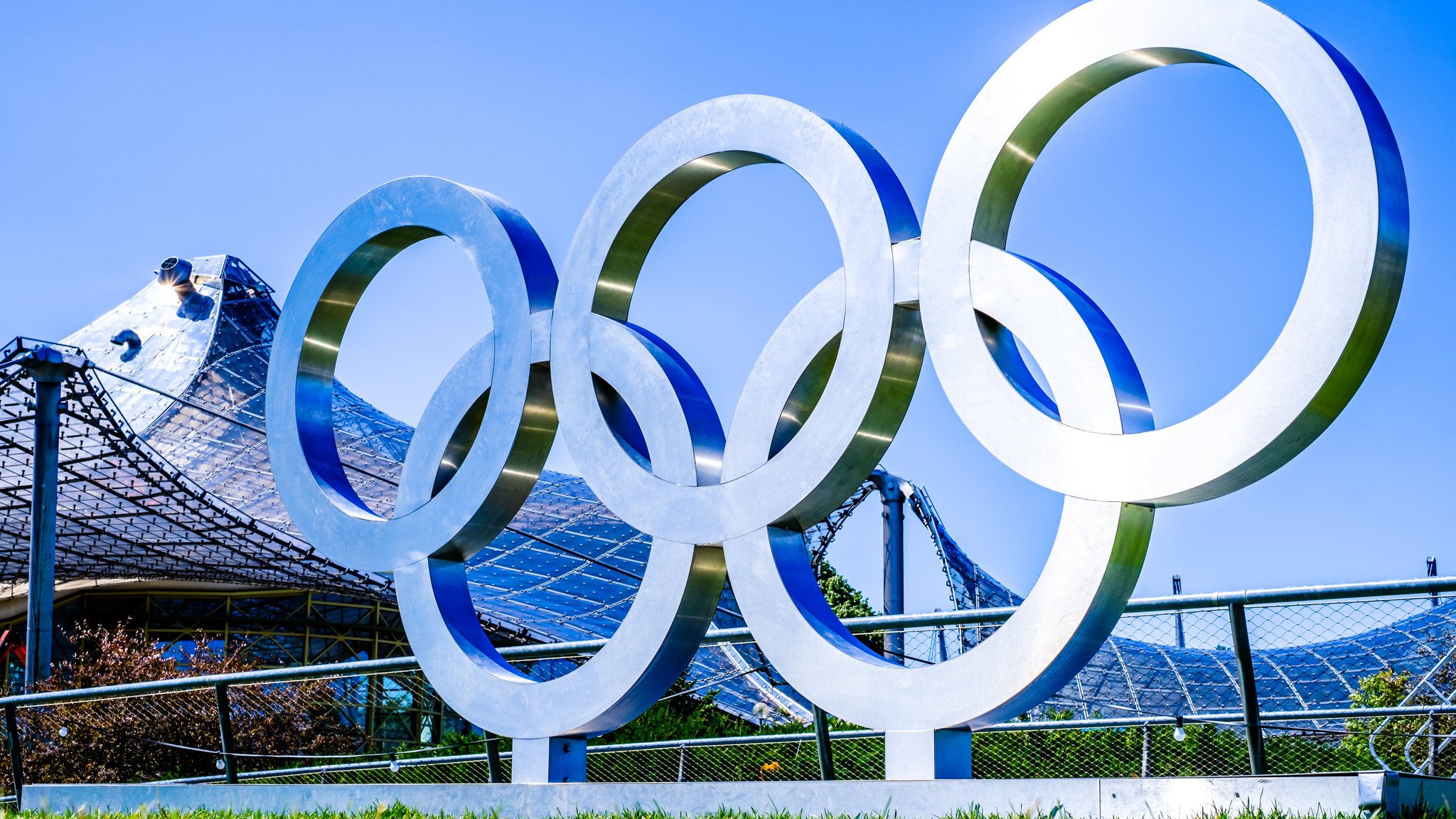 Die olympischen Ringe als Skulptur vor dem Zeltdach des Olympiastadions in München.