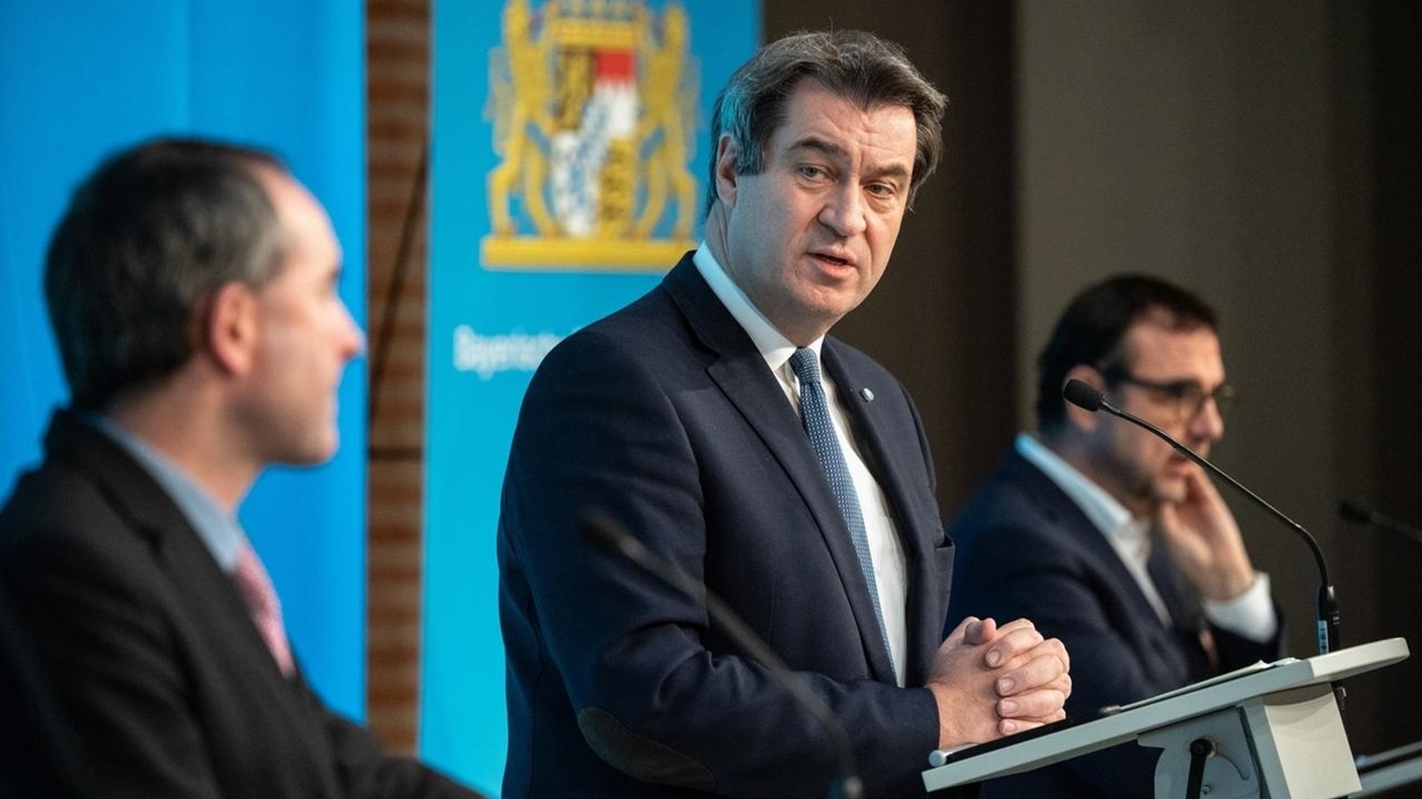 Ministerpräsident Markus Söder (CSU) und zwei Minister bei einer Pressekonferenz.