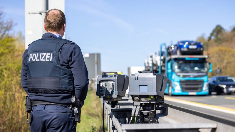 09.04.2025, Hessen, Ehringshausen/Herborn: Ein Polizist steht neben einem Tempo-Blitzer an der Autobahn. Im Rahmen des diesjährigen Speedmarathons werden Geschwindigkeitskontollen auf der Autobahn 45 (A45) zwischen Herborn und Ehringshausen durchgeführt. Foto: Christian Lademann/dpa +++ dpa-Bildfunk +++ | Bild: dpa-Bildfunk/Christian Lademann 09.04.2025, Hessen, Ehringshausen/Herborn: Ein Polizist steht neben einem Tempo-Blitzer an der Autobahn. Im Rahmen des diesjährigen Speedmarathons werden Geschwindigkeitskontollen auf der Autobahn 45 (A45) zwischen Herborn und Ehringshausen durchgeführt. Foto: Christian Lademann/dpa +++ dpa-Bildfunk +++