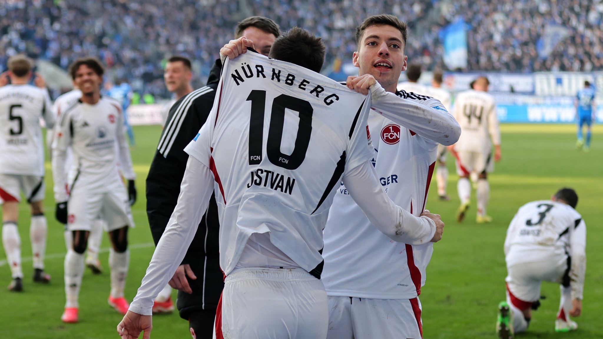 Stefano Tzimas zeigt Siegtorschütze Julian Justvan (Nr. 10) den Fans des 1. FC Nürnberg