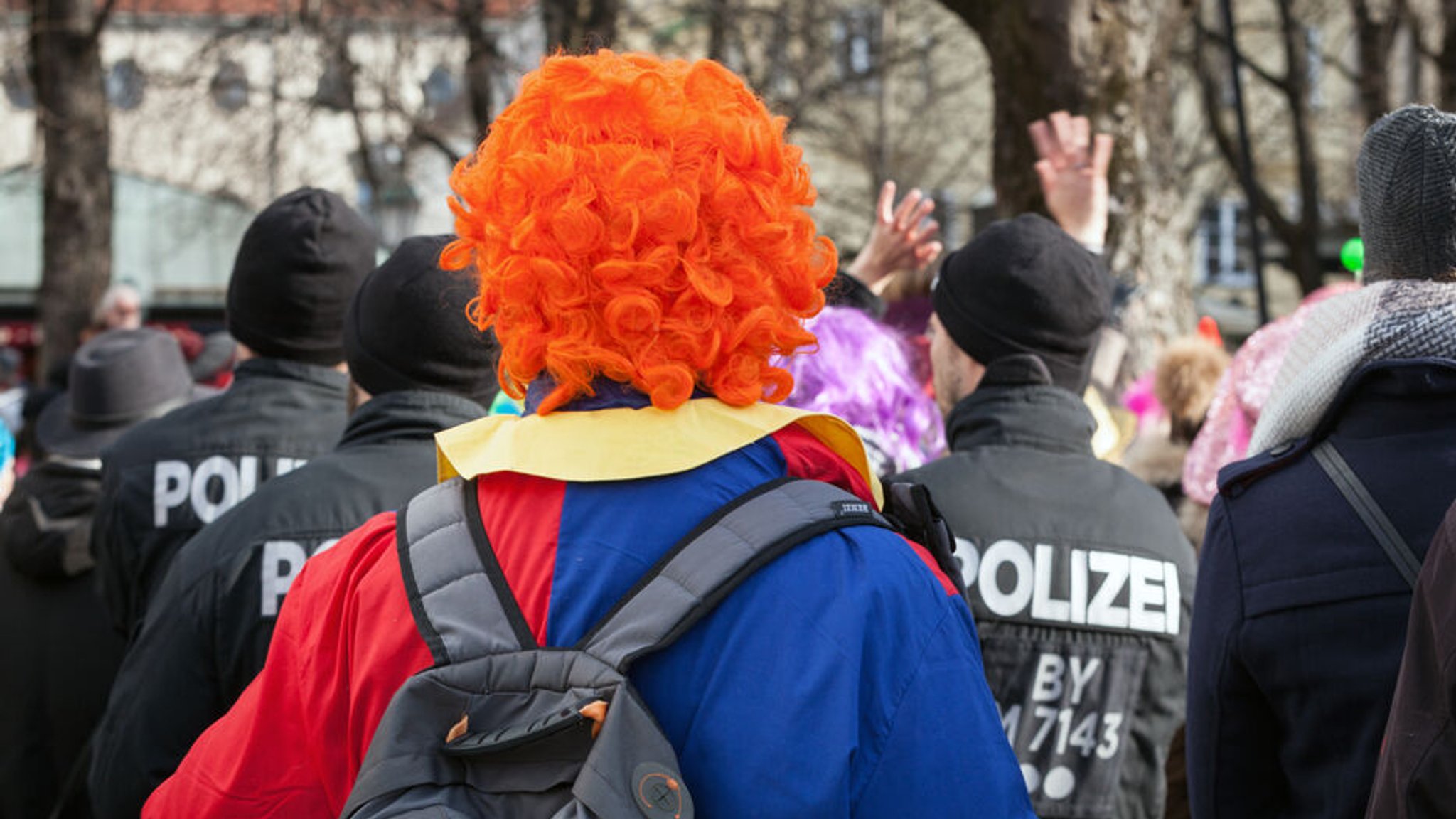 Eine verkleidete Person bei einer Faschingsveranstaltung mit Polizeipräsenz