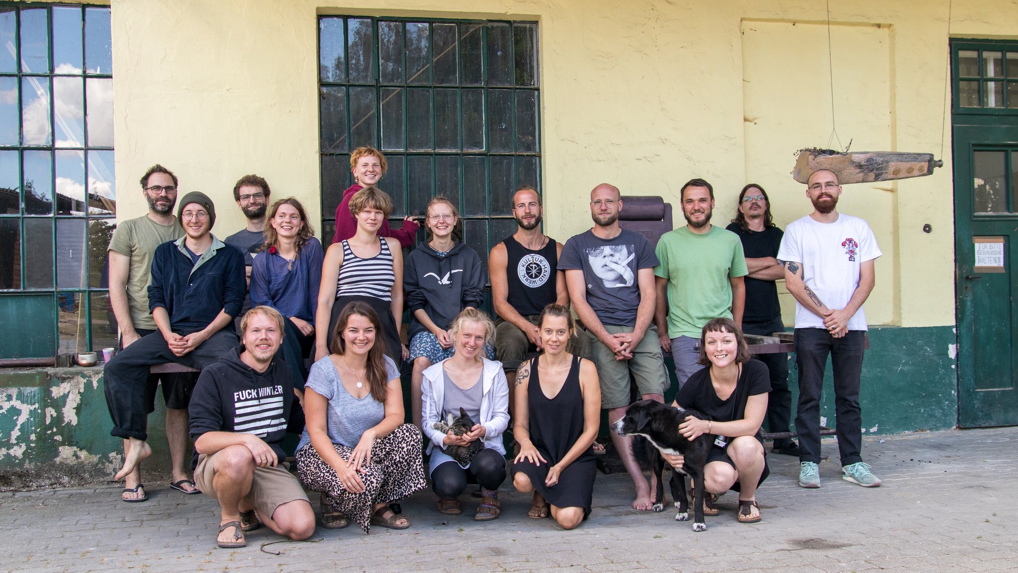 Gruppenfoto junger Menschen vor Fabrikgebäude 