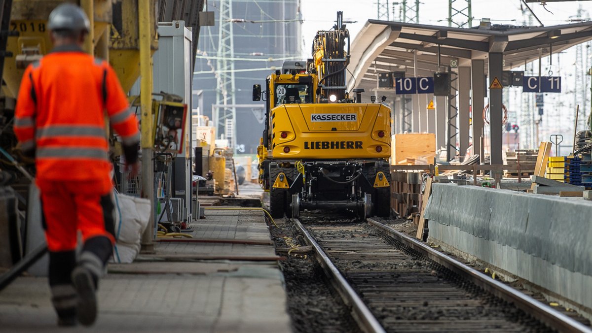 Ein Arbeiter geht während umfangreicher Modernisierungs- und Sanierungsarbeiten entlang der Baustelle an einem Bahnhof.