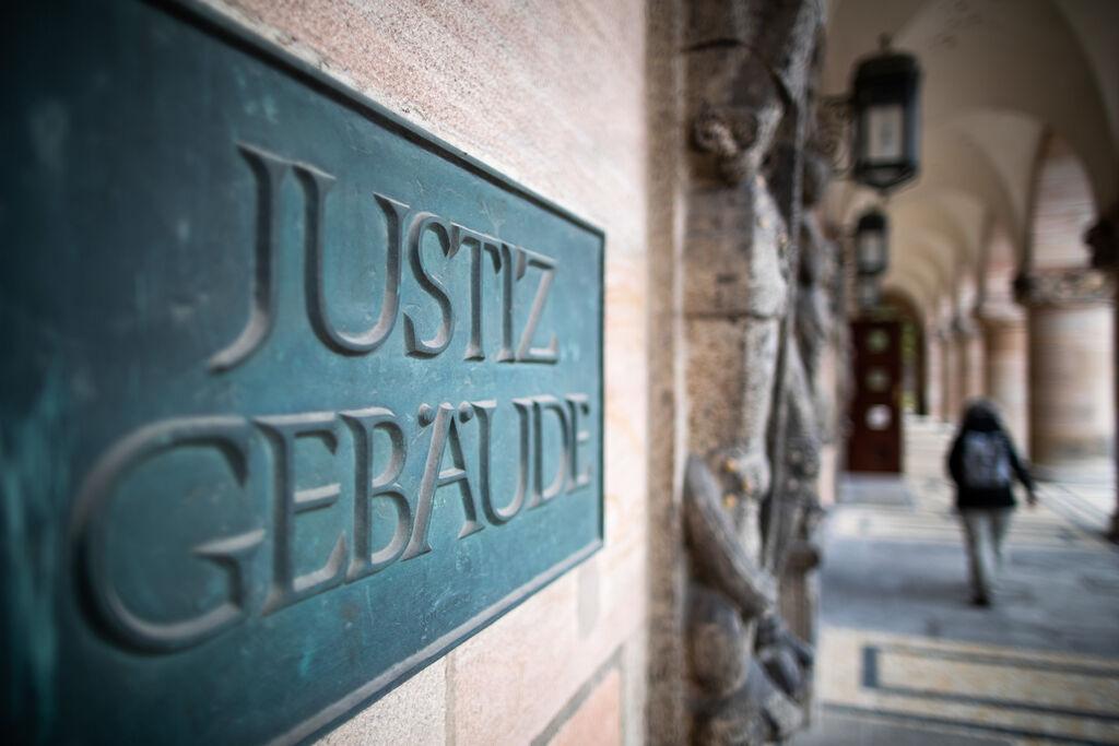 ARCHIV - 18.11.2020, Bayern, Nürnberg: Ein Schild mit der Aufschrift «Justizgebäude» hängt am Eingang vom Landgericht Nürnberg-Fürth. (zu dpa: «Betrug in Millionenhöhe - Betreiber von Pflegedienst verurteilt») Foto: Peter Kneffel/dpa +++ dpa-Bildfunk +++
