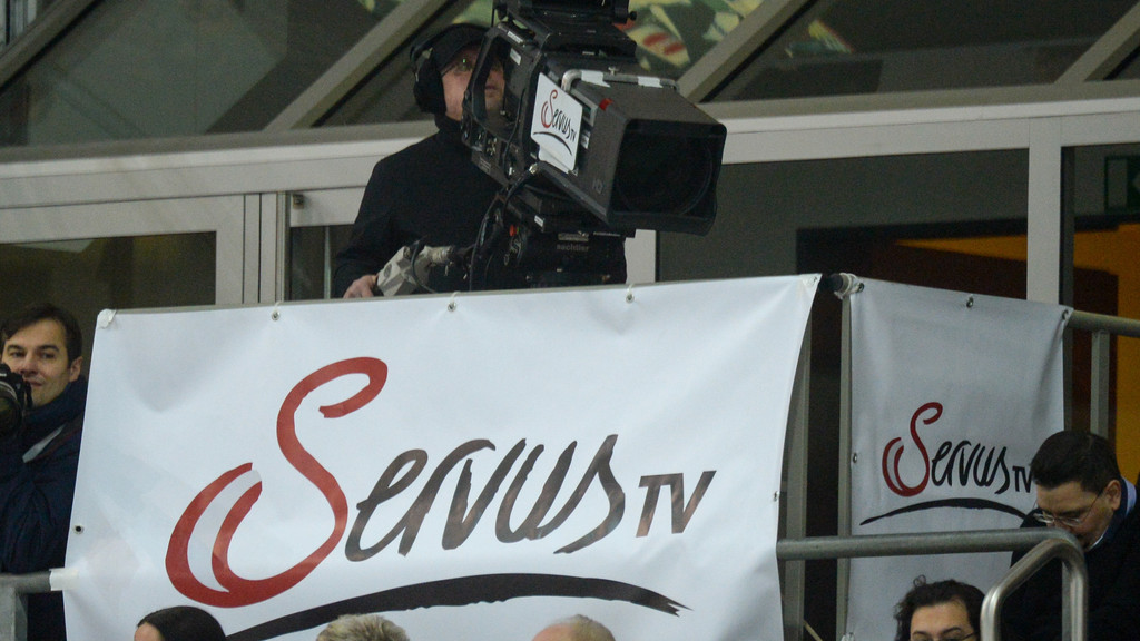 Ein Kameramann von Servus TV filmt bei einem Eishockey-Spiel.