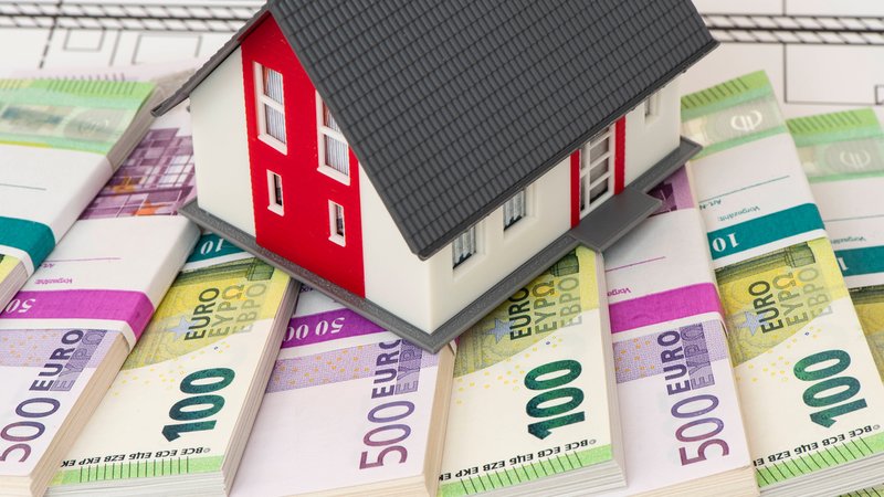 Ein Modellhaus steht symbolisch auf vielen Geldbündel mit Euro Banknoten | Bild: picture alliance / SZ Photo | Wolfgang Filser Ein Modellhaus steht symbolisch auf vielen Geldbündel mit Euro Banknoten