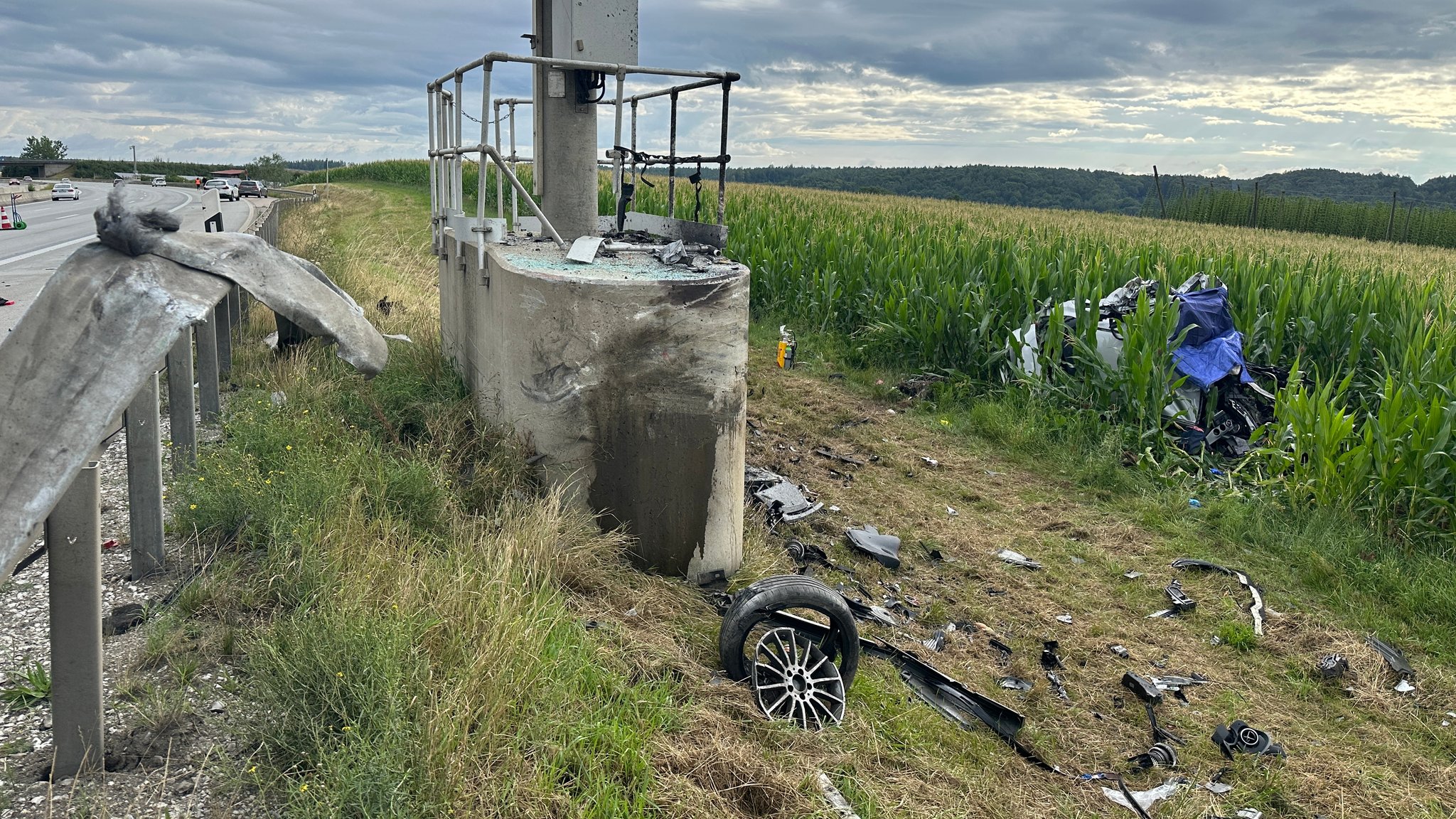 Betonsockel an der A9 bei Pfaffenhofen mit Unfallspuren, Trümmerteile eines Mercedes, Fahrzeugwrack im Maisfeld.