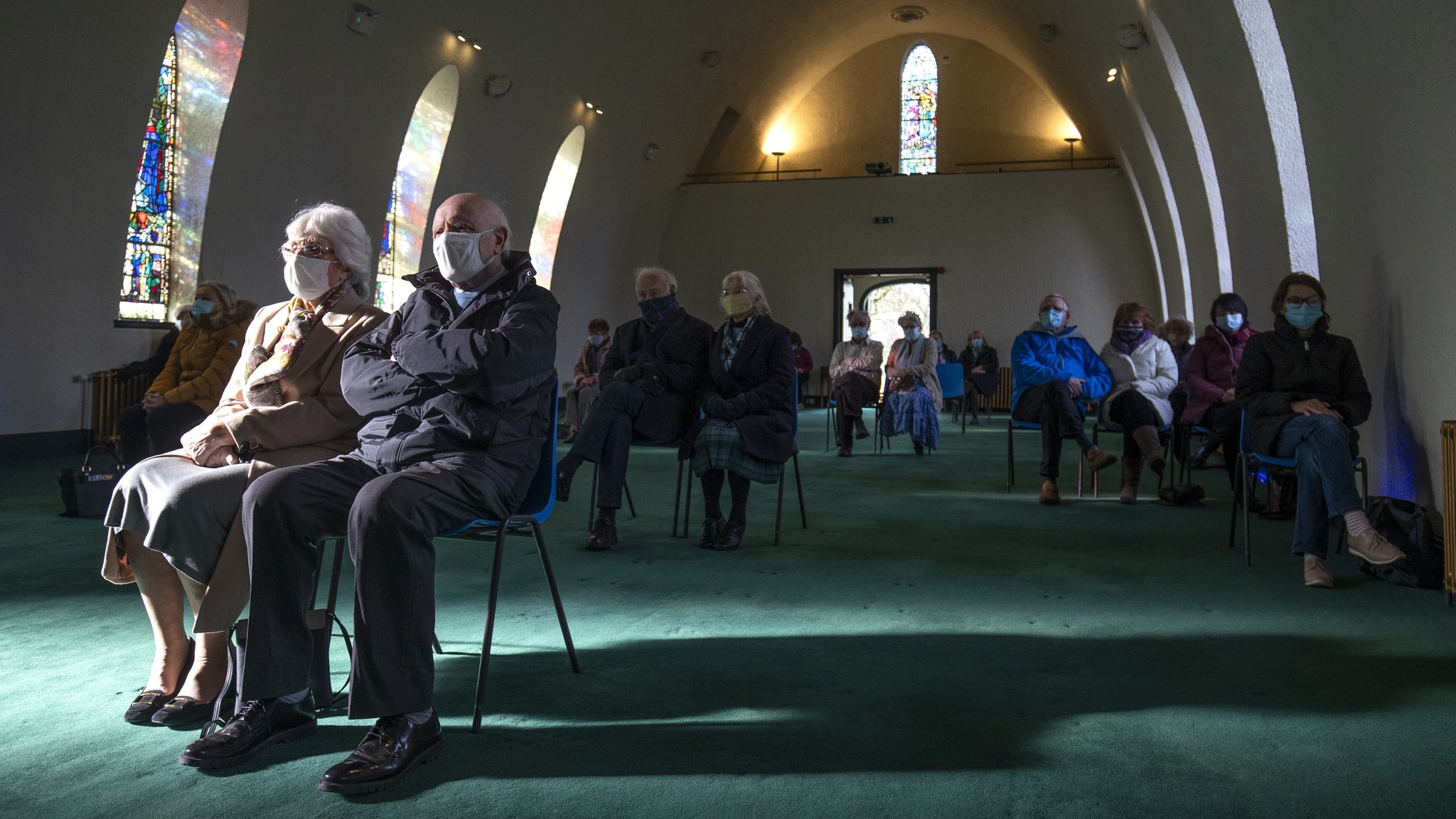 Symbolbild: Besucher einer Kirche mit Sicherheitsanstand und Mundschutz