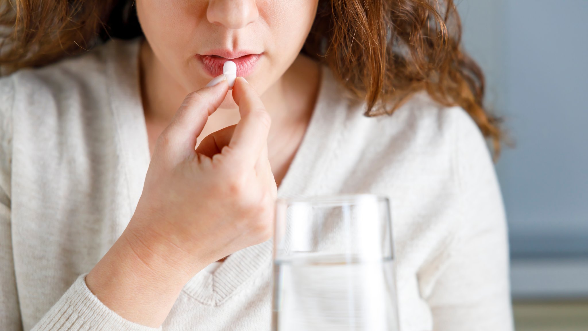 Der Mund einer Frau, zu dem eine Tablette geführt wird und ein Glas Wasser. | Bild: colourbox.de Der Mund einer Frau, zu dem eine Tablette geführt wird und ein Glas Wasser.