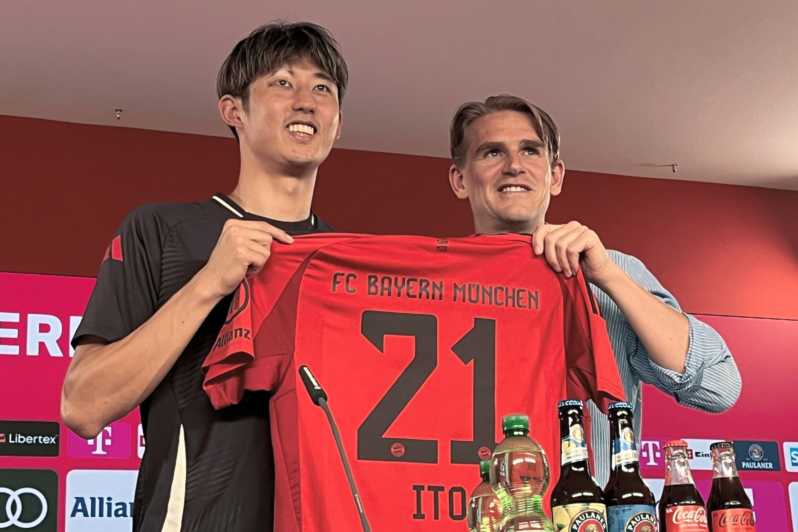 Hiroki Ito (l), Neuzugang des FC Bayern München, und Münchens Sportdirektor Christoph Freund halten während seiner Präsentation Itos neues Trikot.