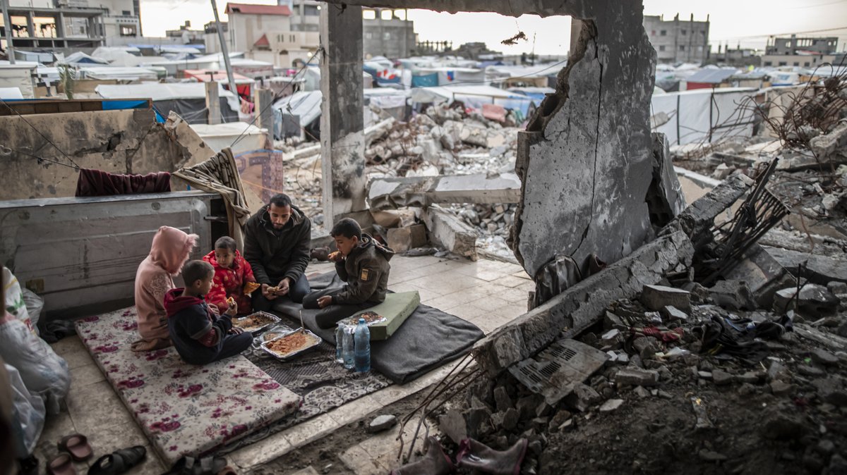 Menschen sitzen in Rafah in der Ruine eines Hauses