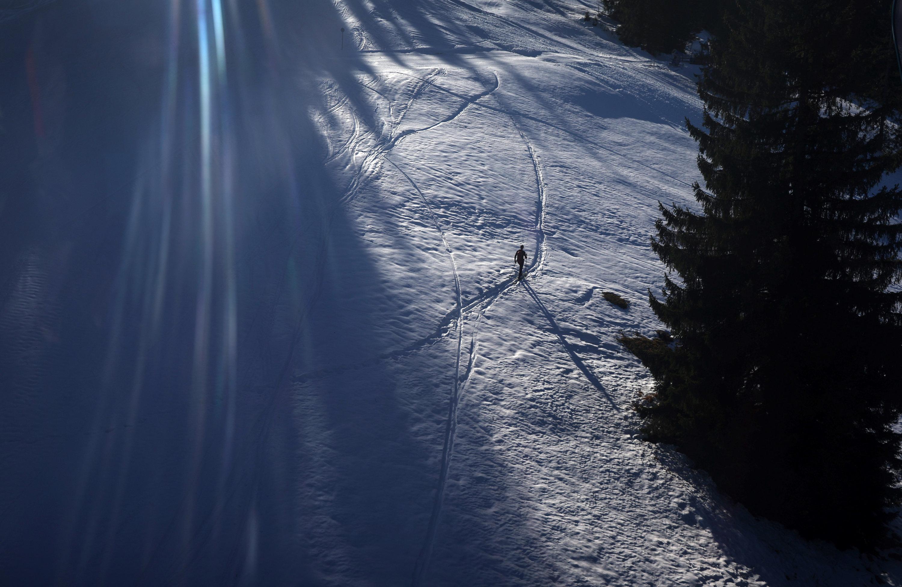 Ein Tourengeher geht im Sonnenschein neben der Skipiste am Söllereck durch den Schnee.