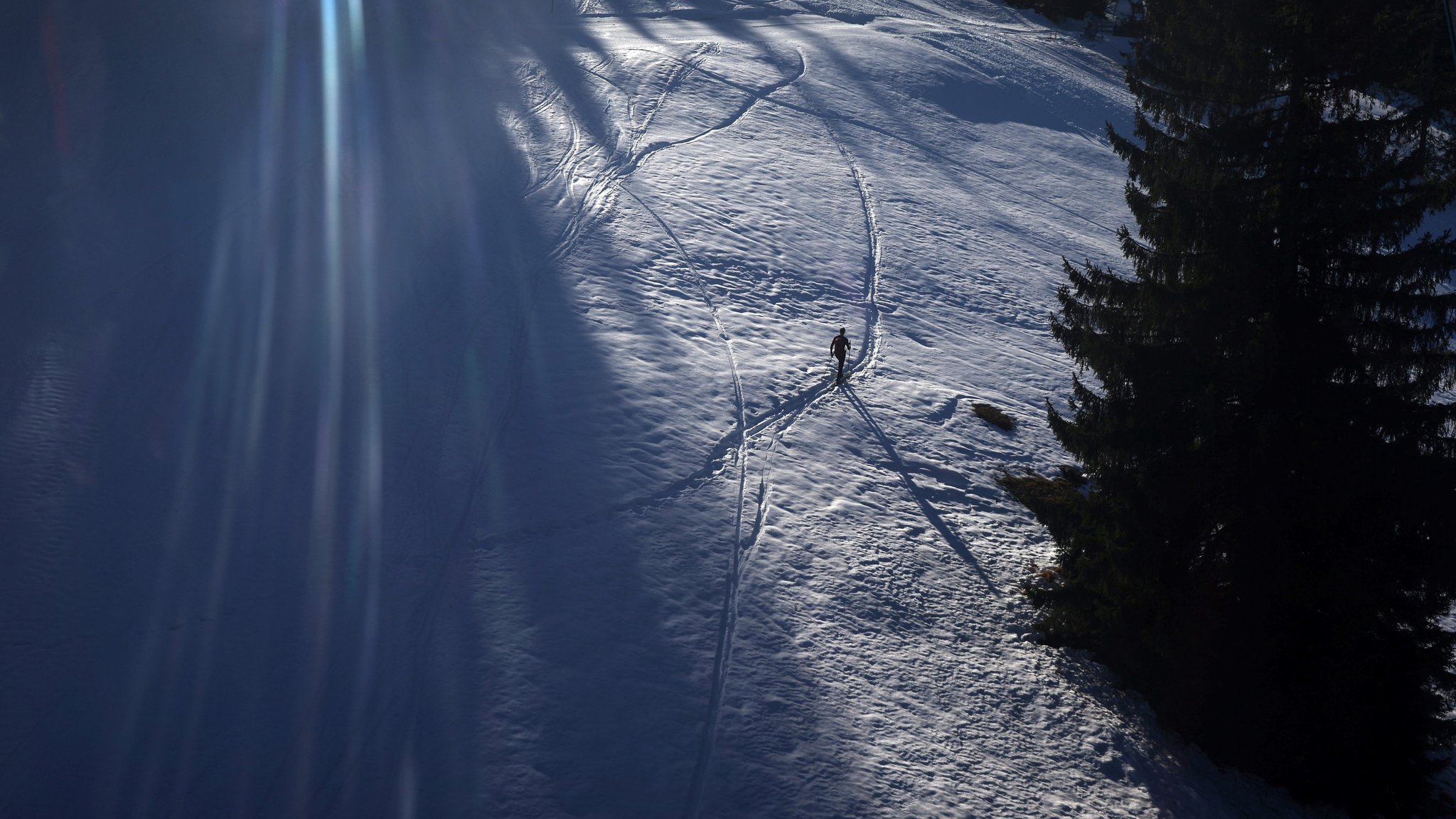 Ein Tourengeher geht im Sonnenschein neben der Skipiste am Söllereck durch den Schnee.